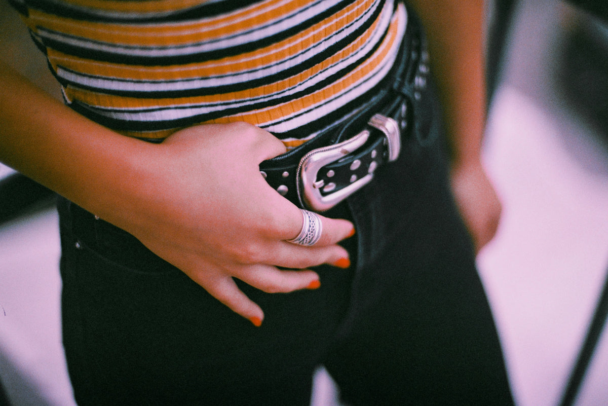 woman's midsection holding her belt with her right hand