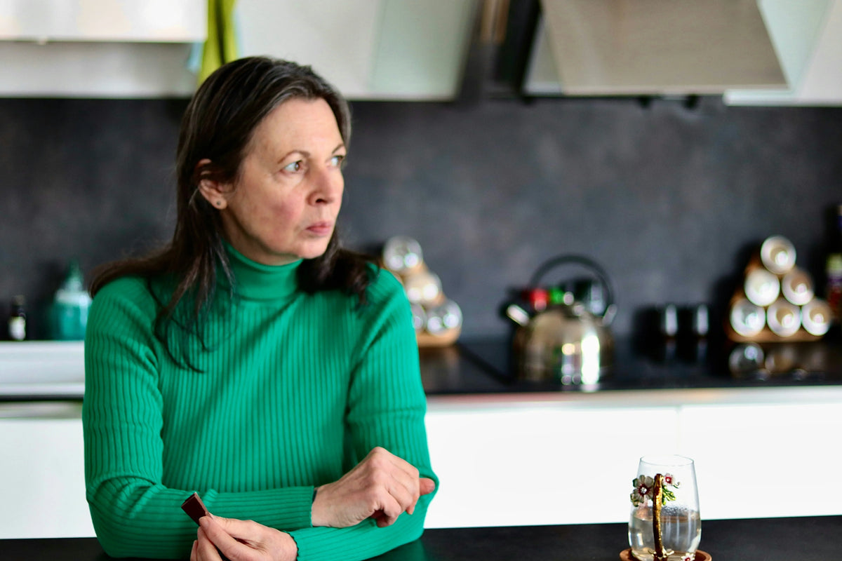 woman in a green shirt standing in a kitchen looking concerned