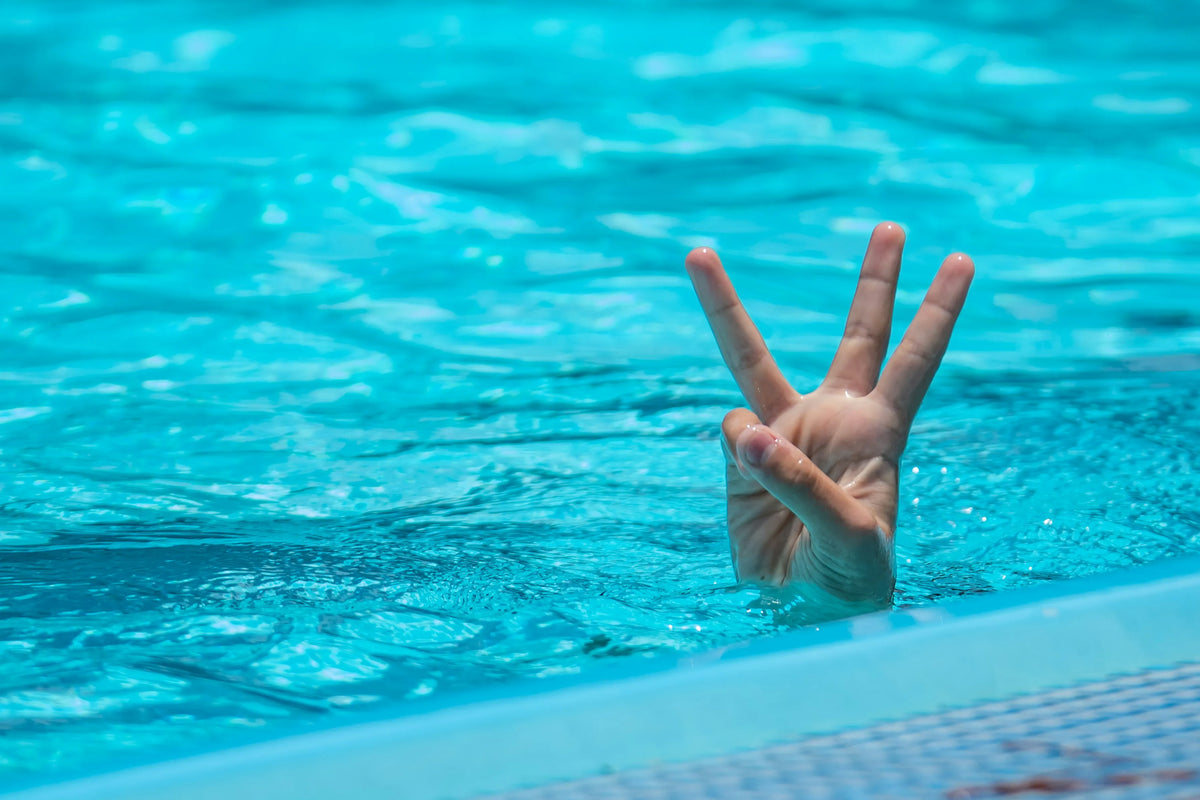 person in a swimming pool holding up 3 fingers