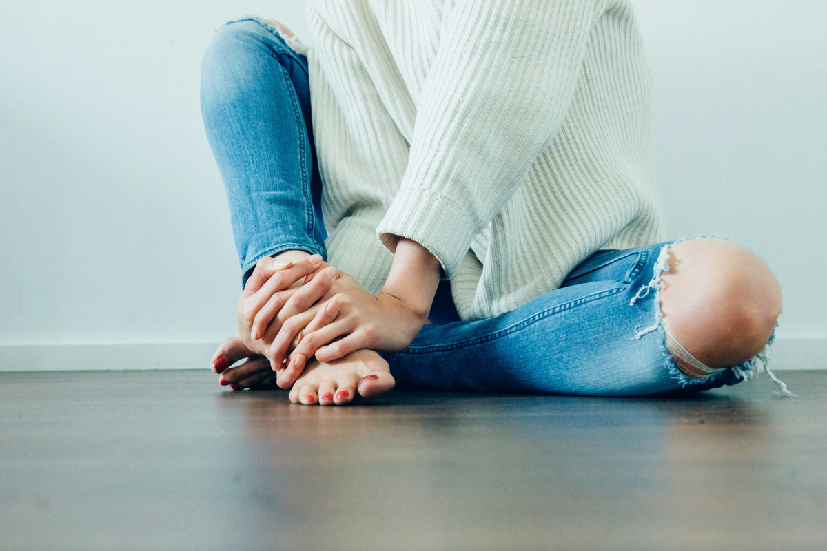 woman sitting on the ground with her hands crossed over her feet