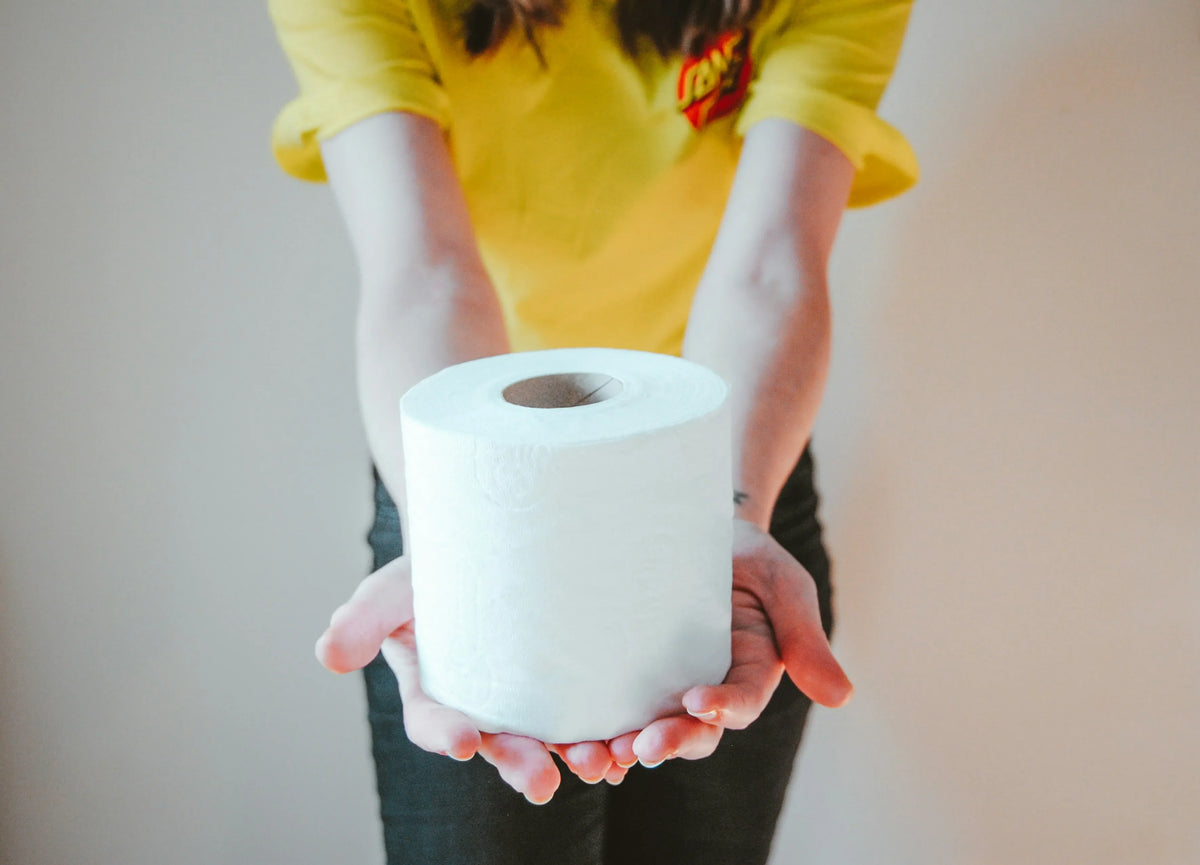woman in a yellow shirt holding toilet paper