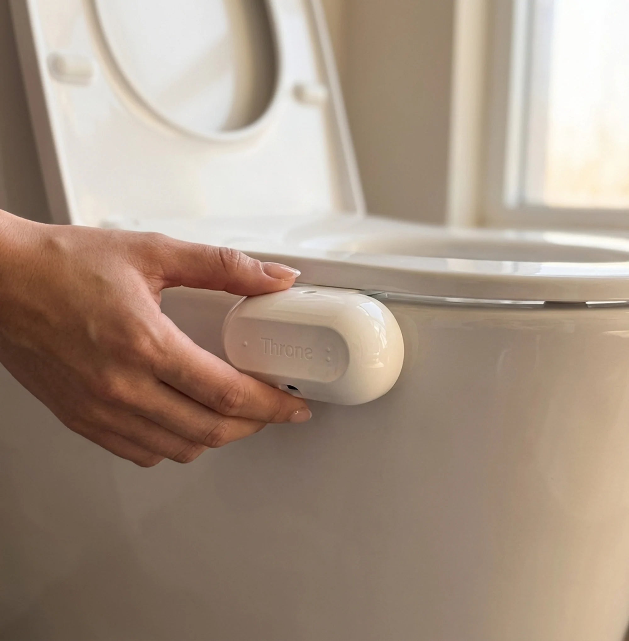 A hand clipping the Throne sensor onto the toilet rim