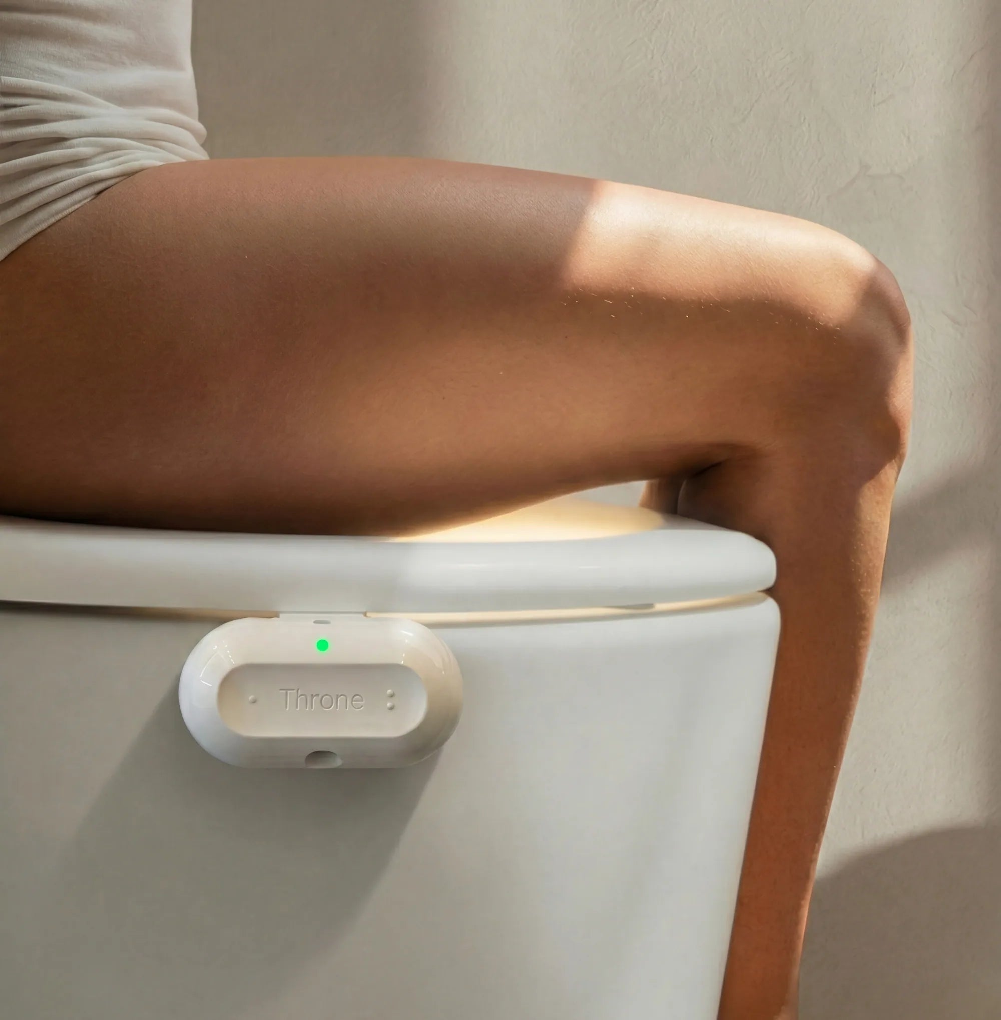 Someone sitting on a toilet with the Throne sensor attached